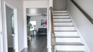 A staircase with wooden steps and a handrail, leading to a living area with a ceiling fan, a sofa, and a coffee table. - Pet-friendly home minutes from Downtown/UGA Campus (Athens)