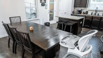 A modern kitchen with dark wood cabinetry, a central island, and a dining area with a dark wood table and chairs.