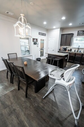 Una cocina moderna con armarios de madera oscura, una isla central y un comedor con mesa y sillas de madera oscura.