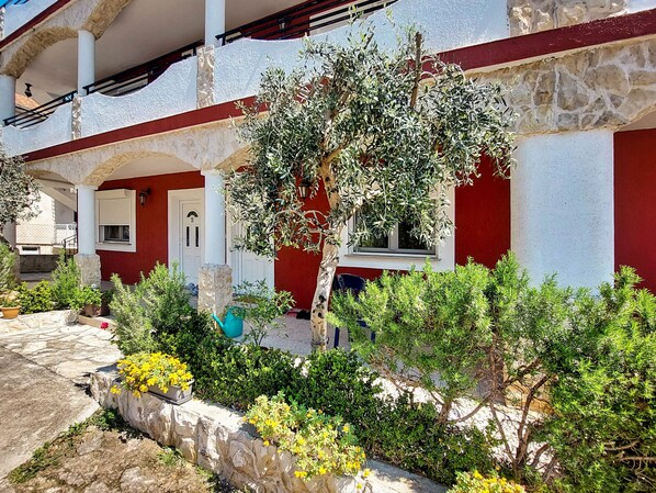 A courtyard with a stone wall, potted plants, and a tree.