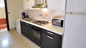 Eine moderne Küche mit Gasherd, Backofen und eingebauter Mikrowelle. Auf der Arbeitsplatte stehen eine Kaffeemaschine und ein Toaster.