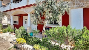 A courtyard with a stone wall, potted plants, and a tree. - Apartment Josip by Interhome (Vodice)