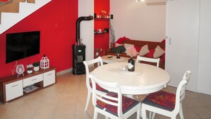 A modern living room with a staircase, a fireplace, a dining area with chairs, and a TV mounted on the wall. - Vacation home Gojko by Interhome (Zadar)