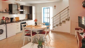 A modern kitchen with a dining area, a washing machine, and a staircase leading to another level. - Vacation home Gojko by Interhome (Zadar)
