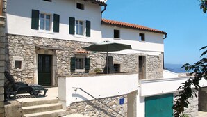 Un bâtiment à deux étages, avec des murs en pierre, une porte verte et une antenne parabolique.