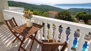 A wooden table and chairs on a balcony with a white balustrade, overlooking a scenic landscape with hills and a body of water. - Albertina by Interhome (Mošćenička Draga)