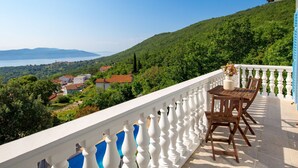 A balcony with a white balustrade, a wooden table with two chairs, and a view of a lake and hills. - Albertina by Interhome (Mošćenička Draga)