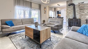 Een moderne woonkamer met een grijze bank, een houten salontafel en een stenen open haard.