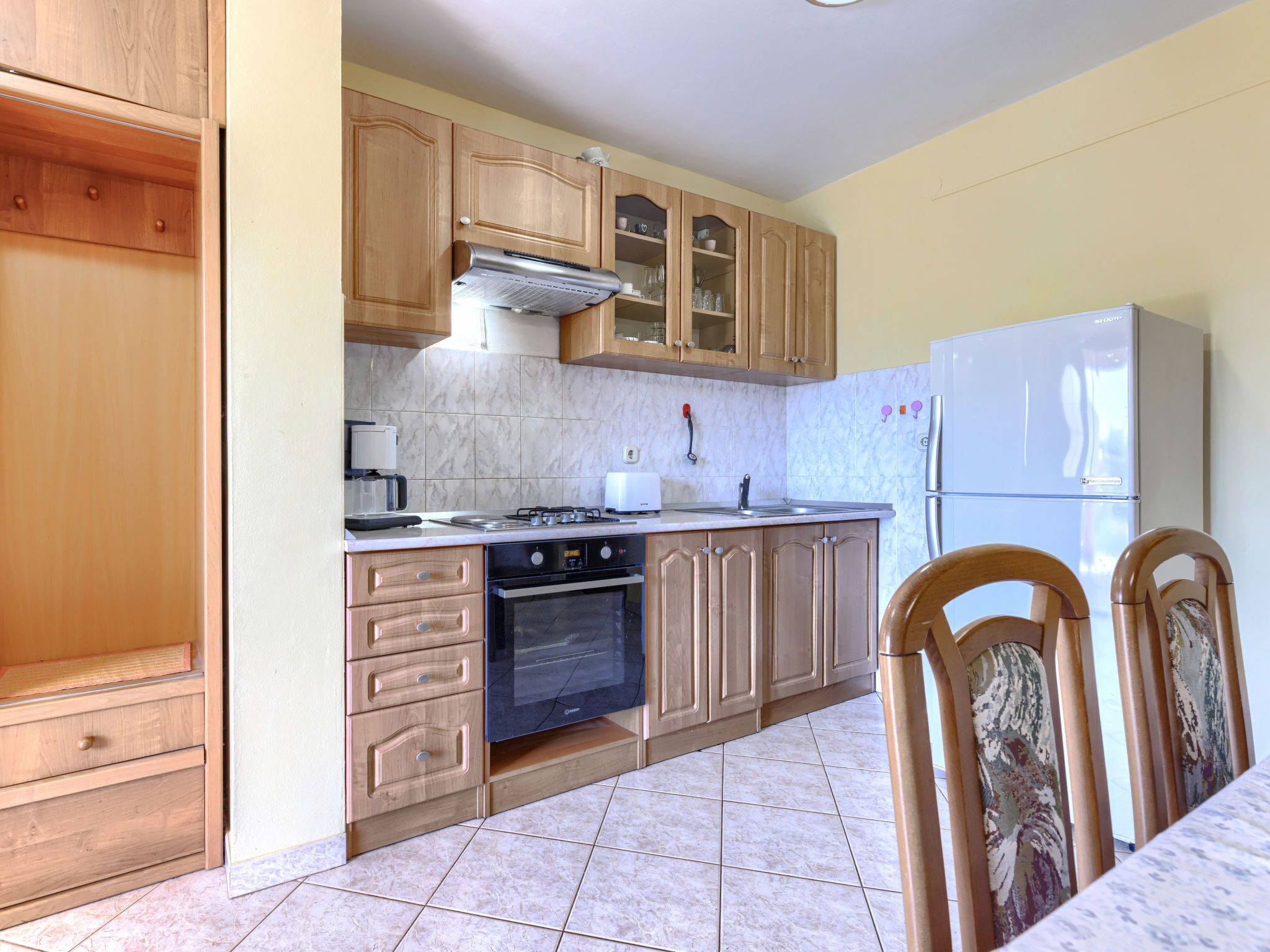 A kitchen with wooden cabinets, a stove, a sink, and a refrigerator.