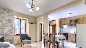 Una stanza con un letto, un tavolo da pranzo con sedie, un angolo cottura con mobili in legno e una parete in pietra.