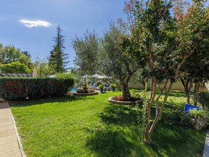 Un jardín bien cuidado con césped, árboles y zonas de estar al aire libre.