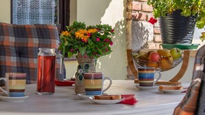 Une table avec une carafe, un vase de fleurs, un panier de fruits et une tasse à rayures.