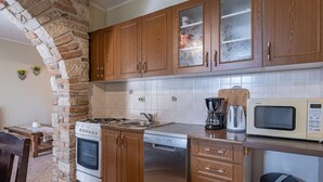 Une cuisine avec des meubles de rangement en bois, une cuisinière, un four à micro-ondes et une machine à café.