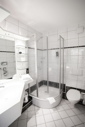 Une salle de bain moderne avec une douche à parois de verre, un lavabo blanc et des toilettes.