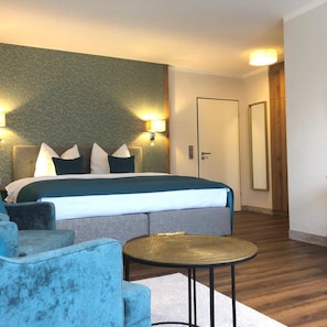 Une chambre d’hôtel avec un lit, deux lampes fixées au mur, une table ronde et une porte.