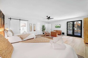 A spacious bedroom with two beds, a ceiling fan, a large window, and a view of the outside. - LUX 7BA/4BA Oasis w/Heated Pool+Spa+Outdoor Living (Las Vegas)