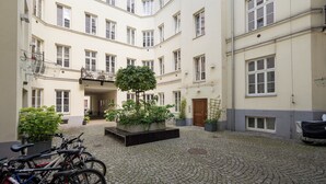 A courtyard with a cobblestone floor, a central planter with plants, and bicycles parked on the left. - Park Praski Two-Level Apartment (Warszawa)