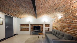 A living room with a brick ceiling, a sofa, a TV, and a fireplace. - Park Praski Two-Level Apartment (Warszawa)