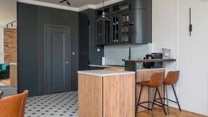 A modern kitchen with a central island, bar stools, and pendant lighting. - City Centre Stylish Apartment (Warszawa)