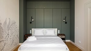 A bedroom with a large bed, two bedside tables, a wall-mounted light fixture, and a partial view of a door. - City Centre Stylish Apartment (Warszawa)