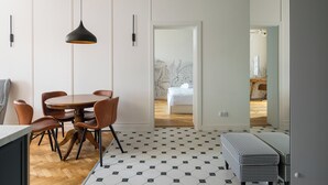 A modern dining area with a round table and chairs, a pendant light, and a patterned floor. - City Centre Stylish Apartment (Warszawa)