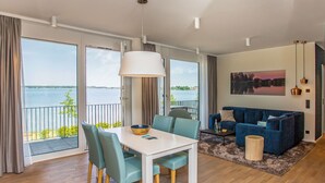 A spacious living area with a dining table, chairs, a sofa, and a view of a lake through large windows. - Maremüritz-Fortuna Müritzblick by Interhome (Waren)