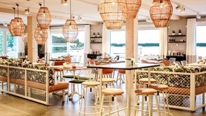 Ein modernes Restaurant mit Korbtellerlampen, Holztischen und gepolsterten Sitzgelegenheiten.