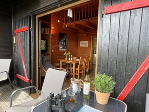 A cozy wooden cabin with a dining area, a table set with a bottle, glasses, and a potted plant.