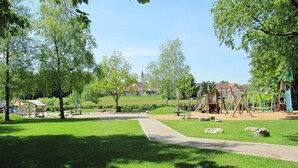 A park with a playground, a path, and a grassy area. - Alpenblick by Interhome (Illmensee)