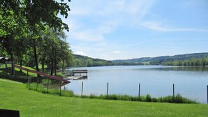 A lakeside park with a wooden dock, a bench, and a fenced walking path. - Alpenblick by Interhome (Illmensee)