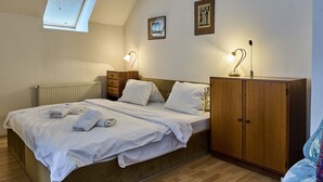 Een slaapkamer met een bed, nachtkastjes, een kledingkast, een radiator en een raam met zonwering.