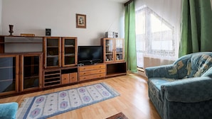 Een woonkamer met een houten kast, een televisie en een groen gordijn.