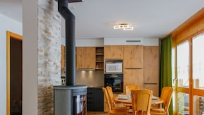 Eine moderne Küche mit Holzofen, Holzschränken und einem Essbereich mit Stühlen.