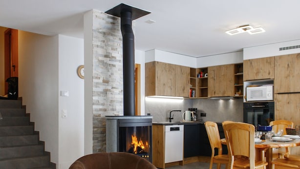 Eine moderne Küche mit Kamin, Holzschränken und einem Essbereich mit Stühlen und Tisch.