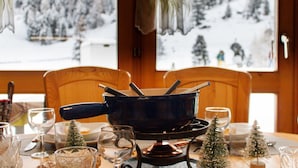 Ein Esstisch mit einem schwarzen Topf, Weingläsern und kleinen Weihnachtsbäumen.