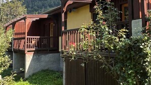 A wooden chalet with a balcony, surrounded by lush greenery and a clear blue sky. - Kunzhof by Interhome (Treffen)