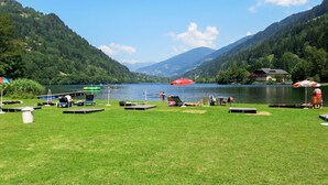 A lakeside setting with grassy areas, a dock, and a building in the background. - Kunzhof by Interhome (Treffen)