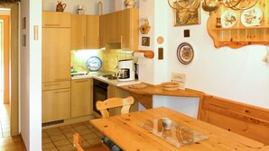 A kitchen with wooden cabinets, a dining table with chairs, a coffee maker, and a chandelier. - Kunzhof by Interhome (Treffen)