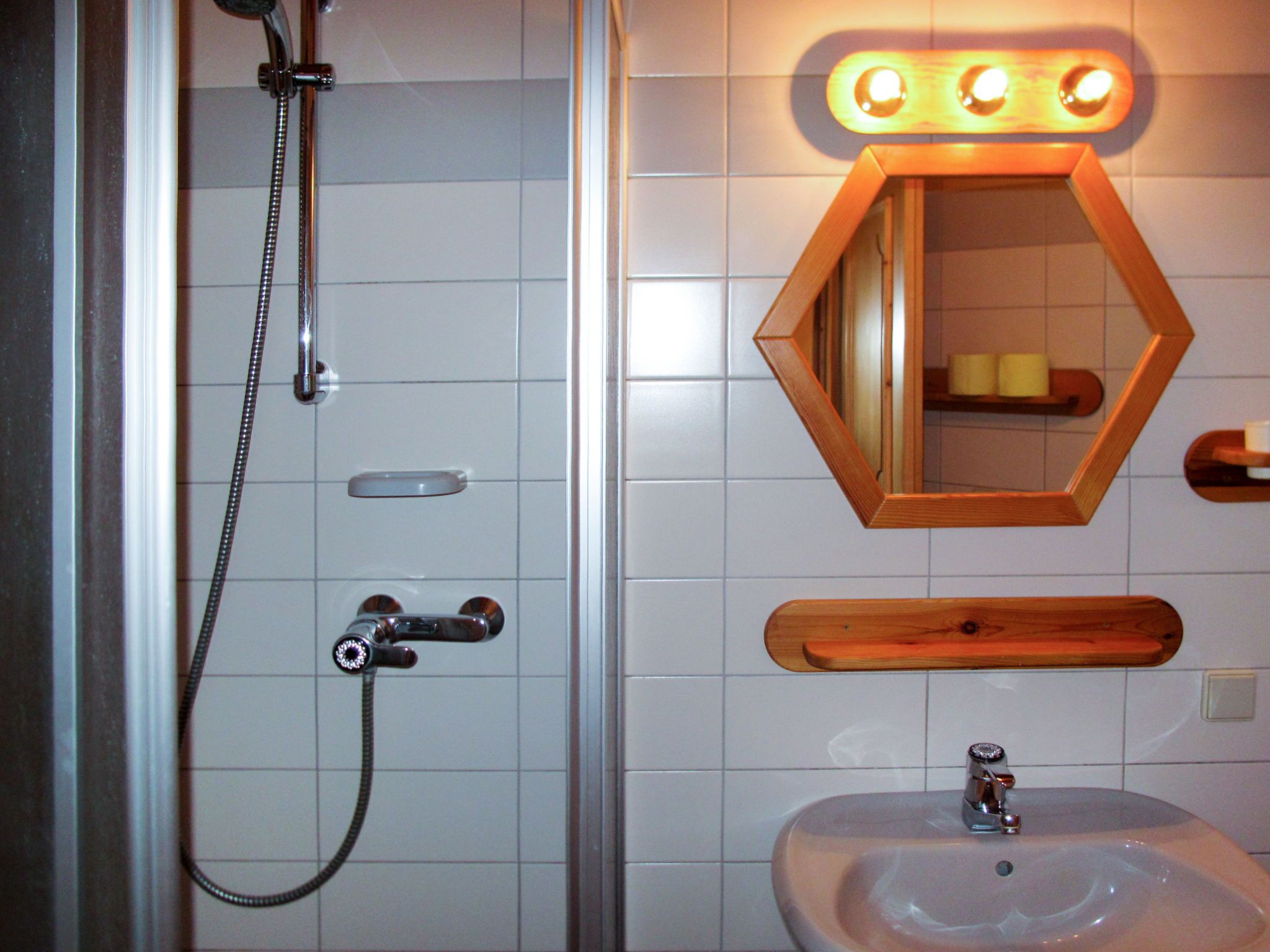 Une salle de bain avec une douche, un lavabo et un miroir.