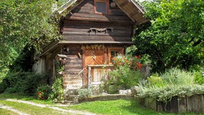 A rustic wooden house with a steeply pitched roof, a front porch with a wooden bench, and a small window above the door. - Kunzhof by Interhome (Treffen)