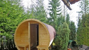 A wooden cabin with a door, a small porch, and a grill in the background. - Walcher by Interhome (Ramsau am Dachstein)