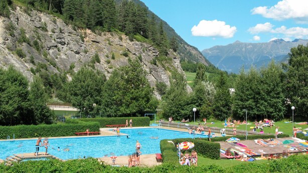 Une piscine entourée d’une végétation luxuriante et de montagnes.