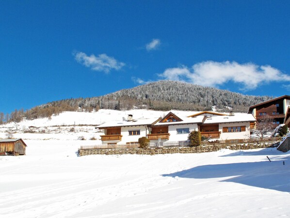 A snow-covered mountain with a wooden chalet-style building in the foreground.