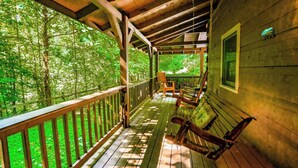 A wooden deck with a railing, wooden benches, and a hanging bag. - Cozy secluded cabin with firepit! - Absolutely Secluded (Gatlinburg)