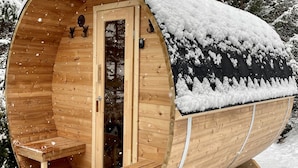 Una cabaña de madera con techo nevado y una sola puerta.