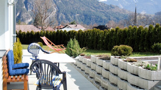 A patio with outdoor furniture, a view of a mountain range, and a neatly arranged garden bed. - Apartment Frisch by Interhome (Imst)