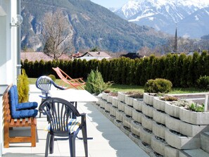 A patio with outdoor furniture, a view of a mountain range, and a neatly arranged garden bed.