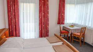 A hotel room with a bed, a small table with chairs, and a window with curtains. - Apartment Frisch by Interhome (Imst)