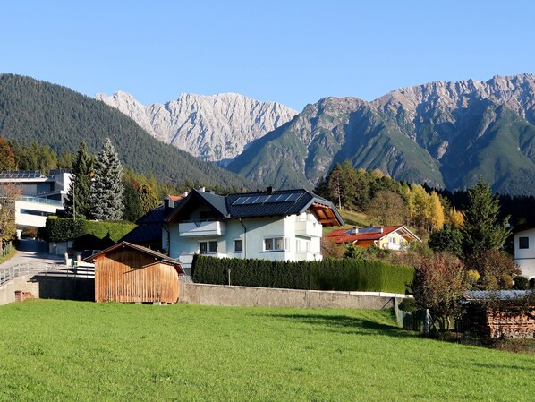 A mountain house with a sloped roof, solar panels, and a view of the surrounding mountains.