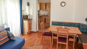 A compact living space with a dining area, kitchenette, and a sofa with floral cushions. - Apartment Frisch by Interhome (Imst)